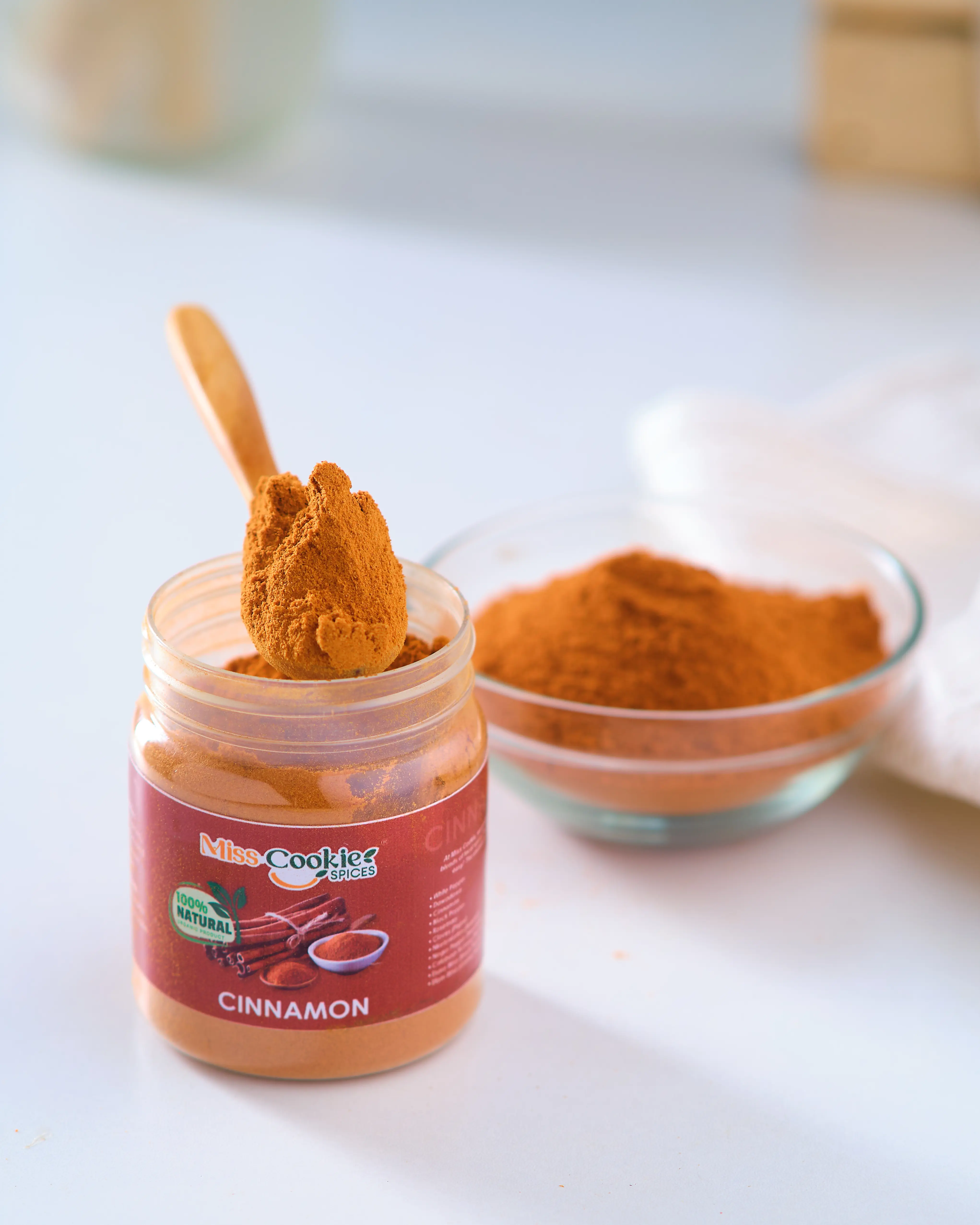 Wooden spoon scooping cinnamon powder from a Miss Cookie jar